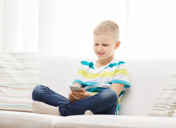 Lächelnder kleiner Junge mit Smartphone zu Hause — Stockfoto