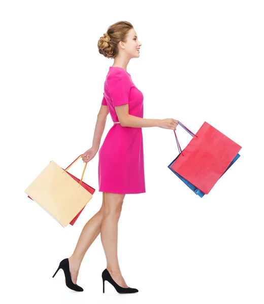 Smiling woman in pink dress with shopping bags — Stock Photo, Image