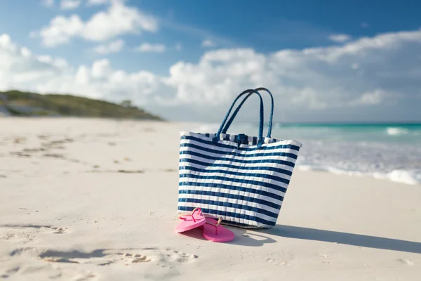 Primo piano di borsa da spiaggia e pantofole in riva al mare — Foto Stock