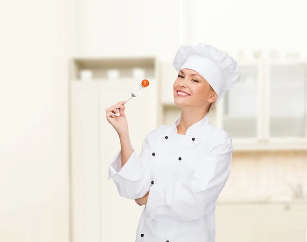 Femme chef souriante avec fourchette et tomate — Photo