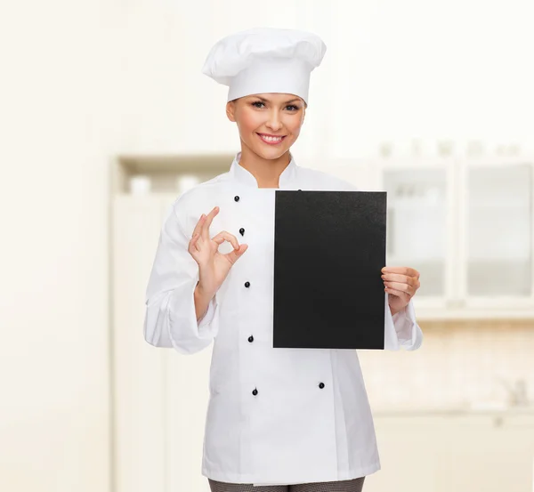 Chef feminino sorridente com papel em branco preto — Fotografia de Stock