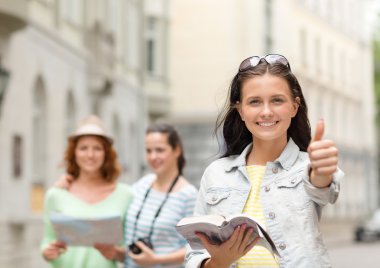 smiling teenage girls with city guide and camera clipart