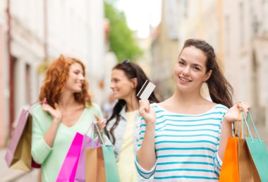 smiling teenage girls with shopping bags on street clipart