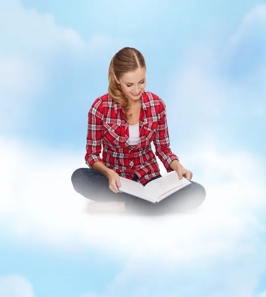 Leende ung kvinna sitter på golvet med bok — Stockfoto