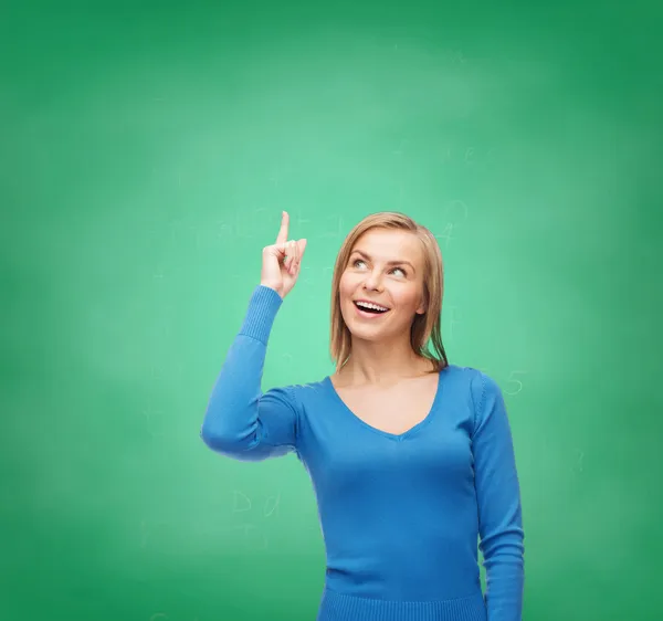 Mujer sonriente señalando con el dedo hacia arriba — Foto de Stock