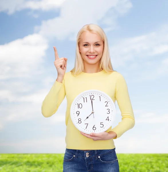 Studente con orologio da parete e dito in su — Foto Stock