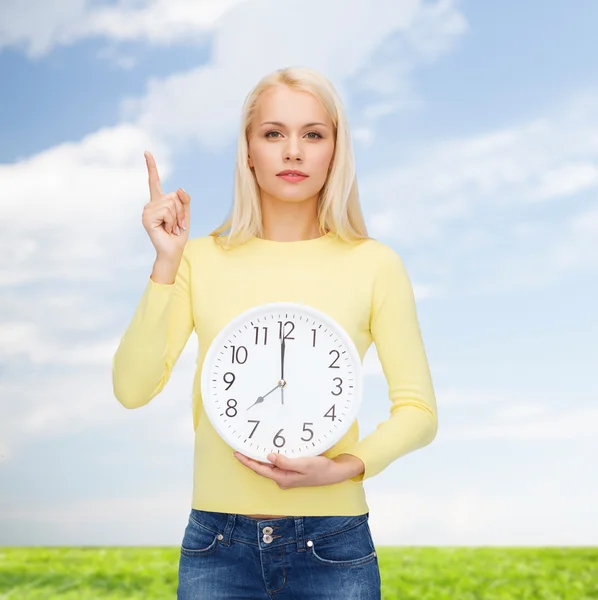 Studente con orologio da parete e dito in su — Foto Stock