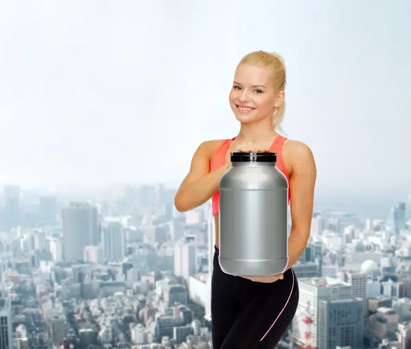 Mujer deportiva sonriente con tarro de proteína —  Fotos de Stock