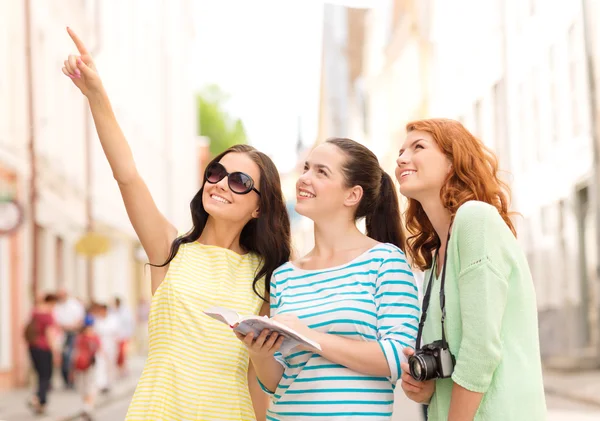 Lachende tienermeisjes met city guide en camera — Stockfoto