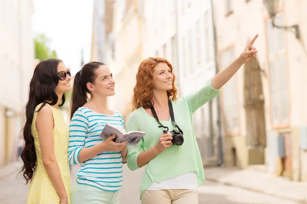 Lachende tienermeisjes met city guide en camera — Stockfoto