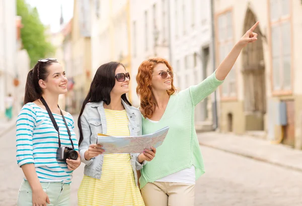 Lachende tienermeisjes met kaart en camera — Stockfoto