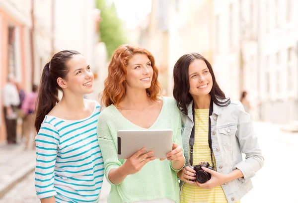 Smiling teenage girls with tablet pc and camera — Stock Photo, Image