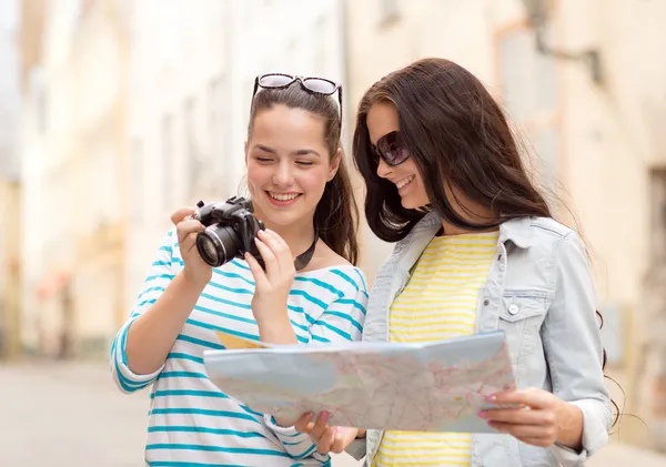 Lachende tienermeisjes met kaart en camera — Stockfoto