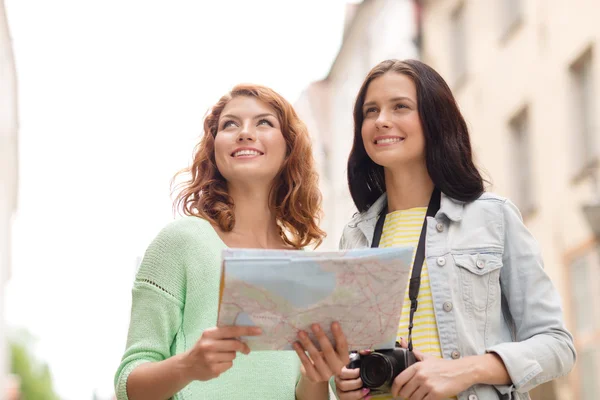 Lachende tienermeisjes met kaart en camera — Stockfoto