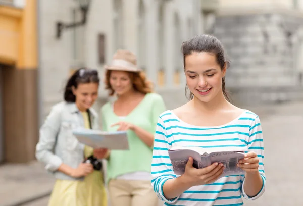 Smiling teenage girls with city guides and camera — Stock Photo, Image