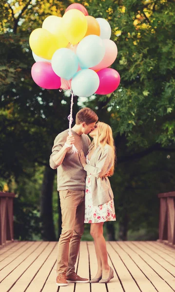 Couple with colorful balloons kissing in the park — Stock Photo, Image