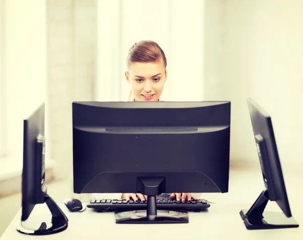 Femme d'affaires avec ordinateur et moniteurs au bureau — Photo