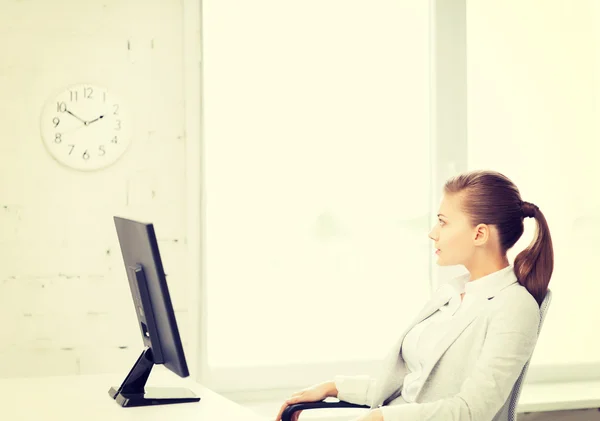 Businesswoman looking at wall clock in office — Stock Photo, Image