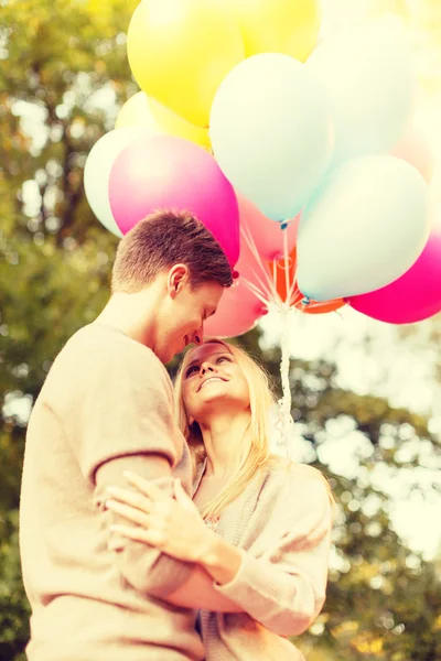 Pareja sonriente con globos de colores en el parque — Foto de Stock