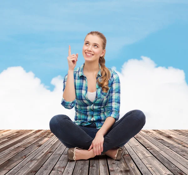 Mujer joven sonriente señalando con el dedo hacia arriba — Foto de Stock