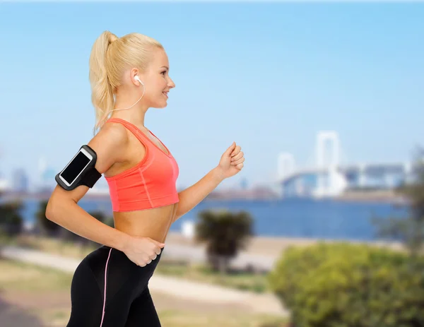 Mujer deportiva corriendo con smartphone y auriculares — Foto de Stock