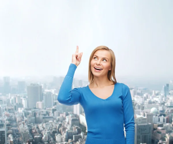 Lächelnde Frau zeigt mit dem Finger nach oben — Stockfoto