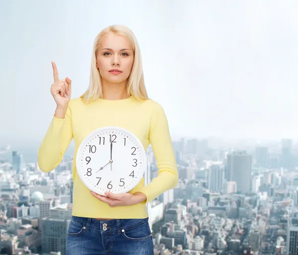 Estudiante con reloj de pared y el dedo arriba — Foto de Stock