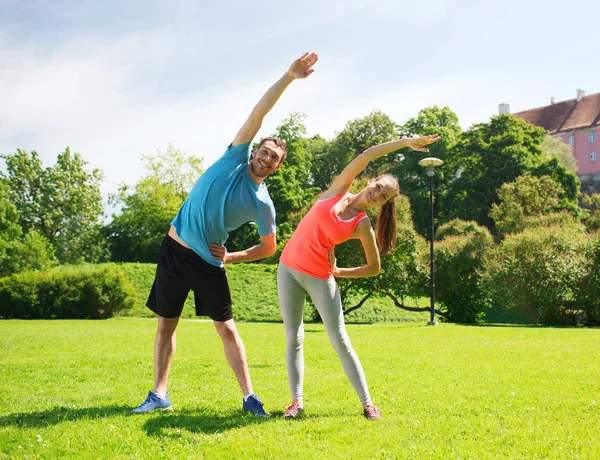 Smiling couple stretching outdoors — Stock Photo, Image