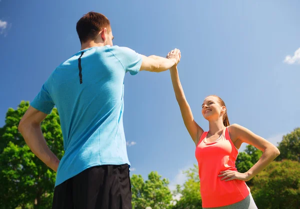 Zwei lächelnde Menschen, die draußen hoch fünf machen — Stockfoto