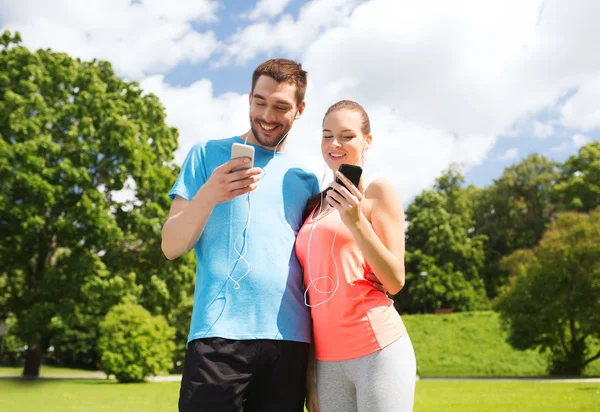 Duas pessoas sorridentes com smartphones ao ar livre — Fotografia de Stock