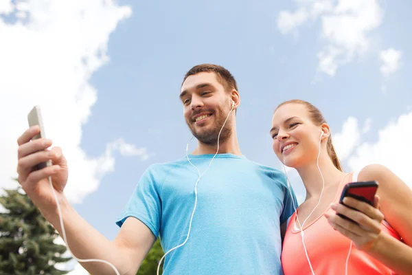 Twee lachende mensen met smartphones outdoors — Stockfoto