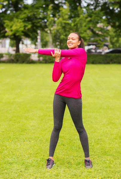 Glimlachend zwarte vrouw die zich uitstrekt been buitenshuis — Stockfoto