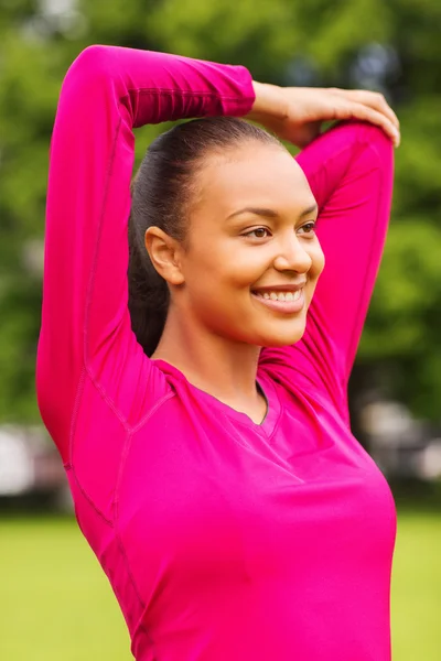 Sorridente donna nera allungamento gamba all'aperto — Foto Stock