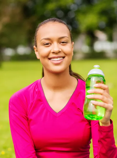 Smiling teenage girl showing bottle — Stock Photo, Image