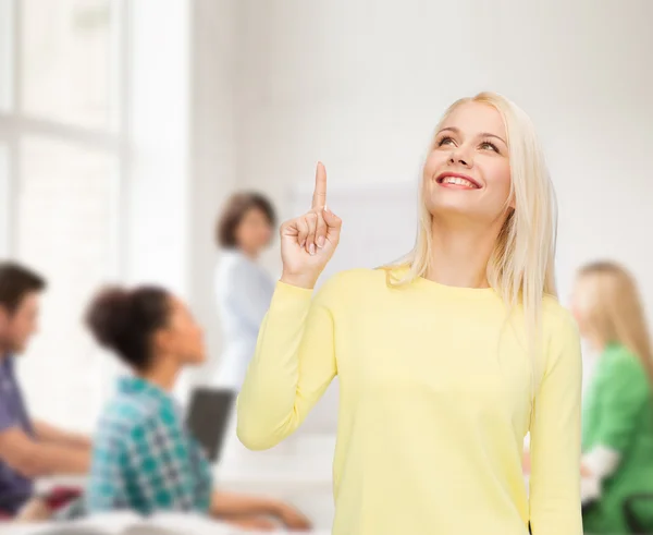Lächelnde Frau zeigt mit dem Finger nach oben Stockfoto