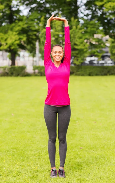 Sonriente negro mujer estirando la pierna al aire libre —  Fotos de Stock