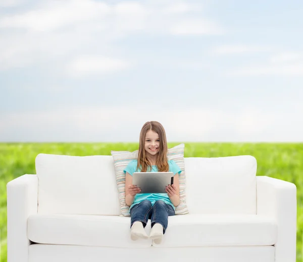 Liten flicka sitter på soffan med TabletPC — Stockfoto