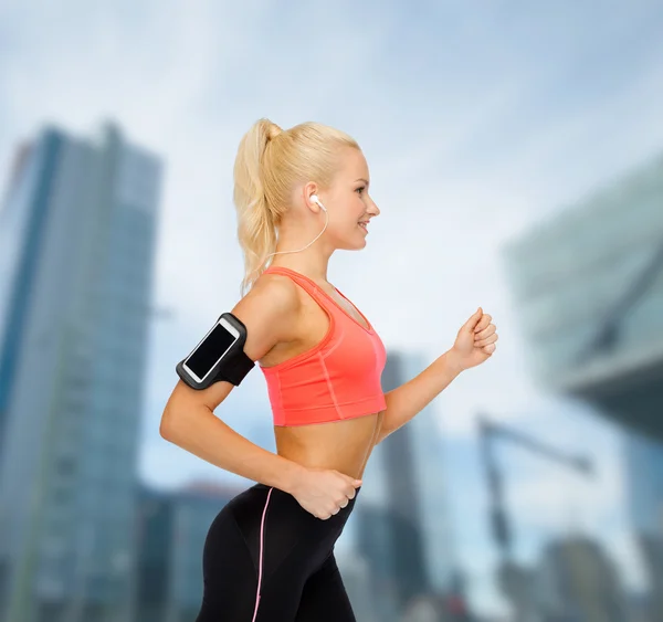 Mujer deportiva corriendo con smartphone y auriculares — Foto de Stock