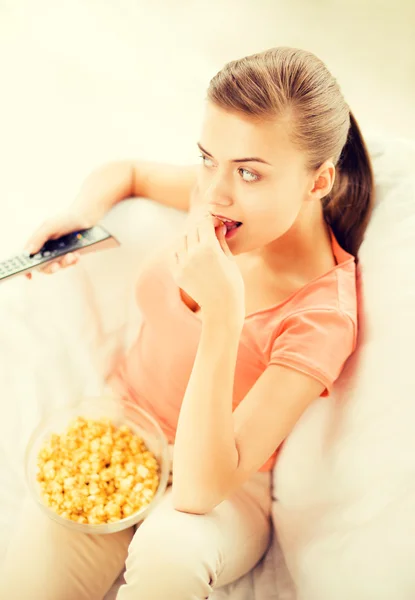 Frau schaut fern und isst Popcorn Stockfoto