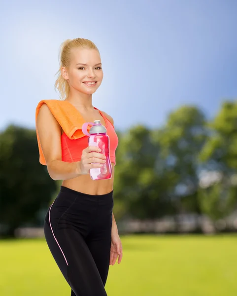 Sorrindo mulher desportiva com garrafa de água e toalha — Fotografia de Stock