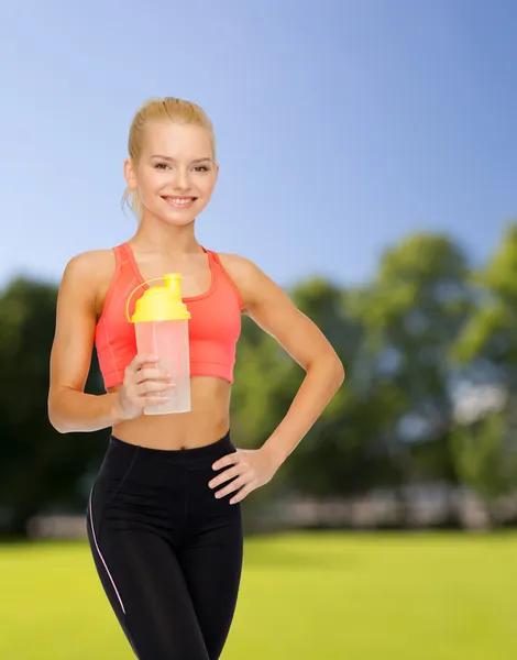 Улыбающаяся спортивная женщина с бутылкой протеинового коктейля — стоковое фото