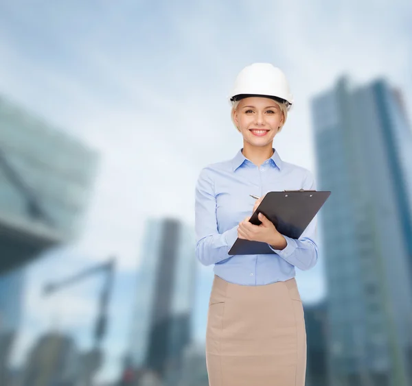 Smiling businesswoman in helmet with clipboard — Stock Photo, Image