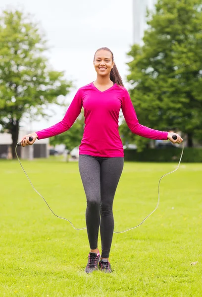 Mujer sonriente haciendo ejercicio con cuerda de salto al aire libre — Foto de Stock