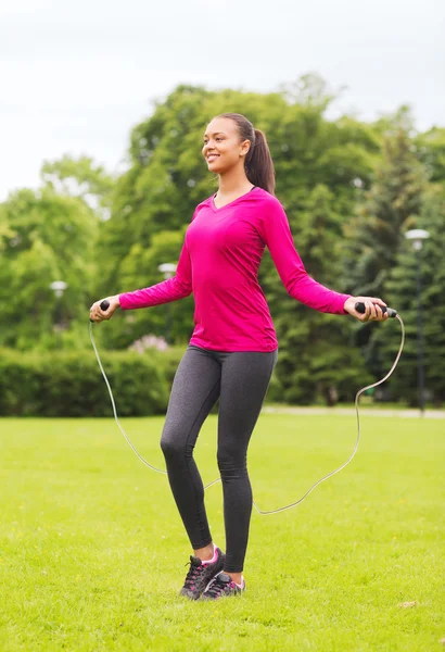 Mujer sonriente haciendo ejercicio con cuerda de salto al aire libre — Foto de Stock