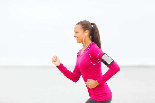 Smiling young woman running outdoors — Stock Photo, Image