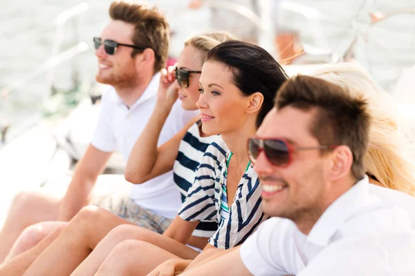 Amigos sonrientes sentados en la cubierta del yate — Foto de Stock