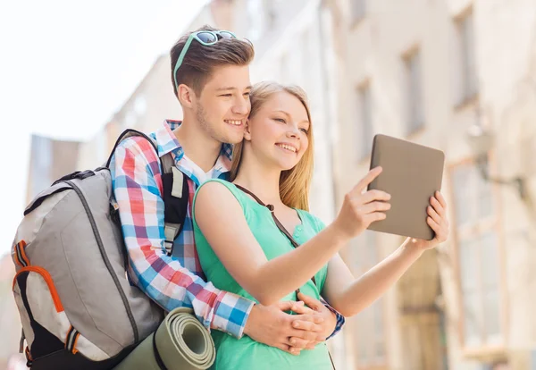 Smiling couple with tablet pc and backpack in city — Stock Photo, Image