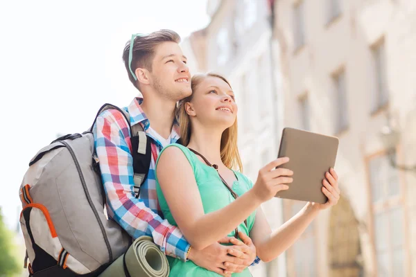 Casal sorridente com tablet pc e mochila na cidade — Fotografia de Stock