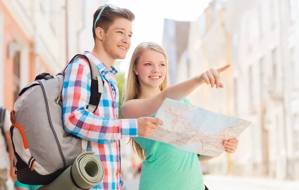 Sorrindo casal com mapa e mochila na cidade — Fotografia de Stock