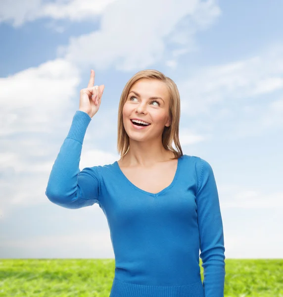 Mujer sonriente señalando con el dedo hacia arriba —  Fotos de Stock